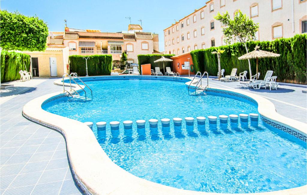 duży basen z krzesłami i budynek w obiekcie Cozy Apartment In Torrevieja With Wifi w mieście Torrevieja