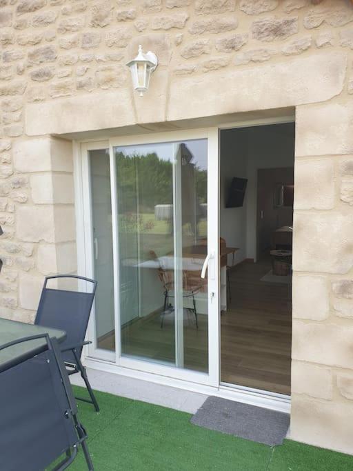 une porte coulissante en verre sur un patio avec une table dans l'établissement Gîte et piscine l'écrin aux oliviers en Cévennes, à Saint-Christol-lès-Alès