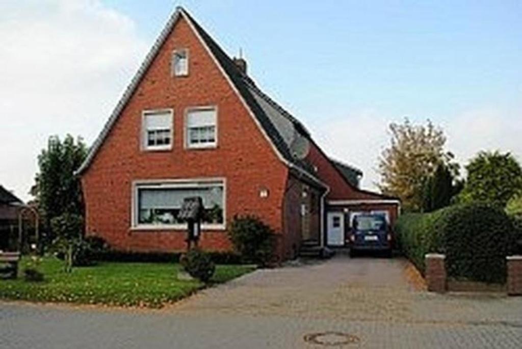 a large red brick house with a driveway at Ferienwohnung Krummhörn Upleward in Krummhörn