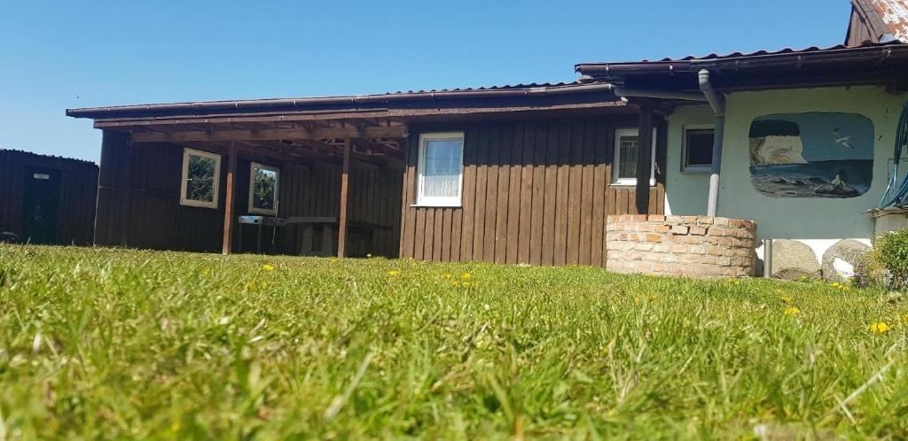 a house with a grass field in front of it at Wunderschönes Ferienhaus in Groß Schoritz mit Garten, Grill und Terrasse in Garz-Rügen