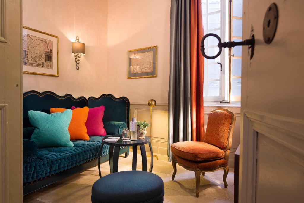 a living room with a blue couch with colorful pillows at La Maison d&#39;Uzès Relais &amp; Châteaux in Uzès