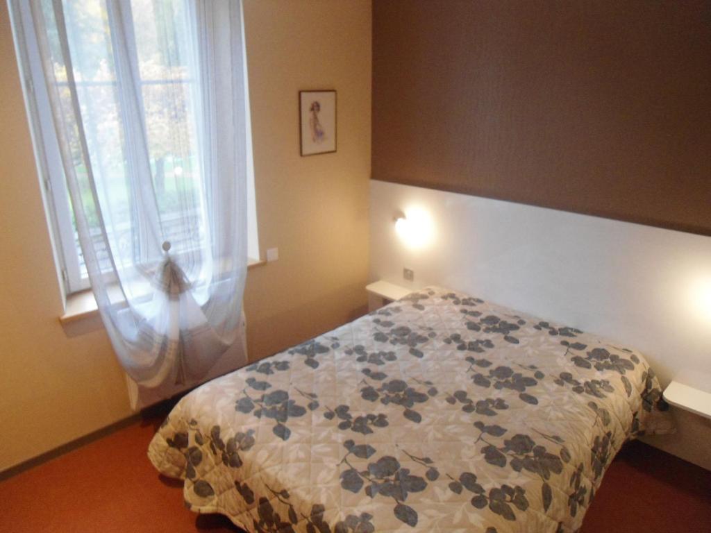 a bedroom with a bed with a blue and white blanket at Hôtel Des Vosges in Contrexéville