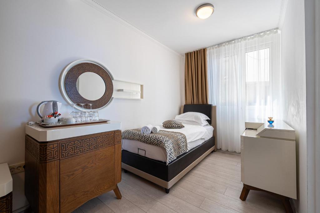 a bedroom with a bed and a mirror and a sink at Hotel Adrović in Sveti Stefan