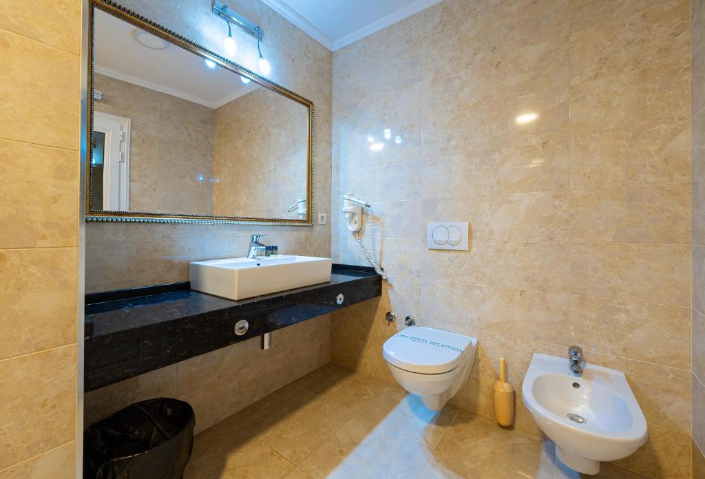 a bathroom with a sink and a toilet and a mirror at Hotel Adrović in Sveti Stefan