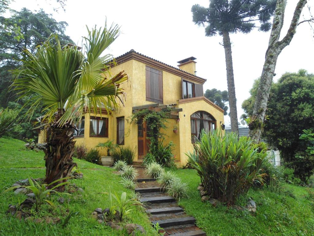 una casa amarilla con una palmera delante de ella en Aconchego Jardim dos Pinheiros, en Canela