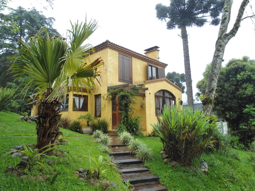 a yellow house with a palm tree in front of it at Aconchego Jardim dos Pinheiros in Canela