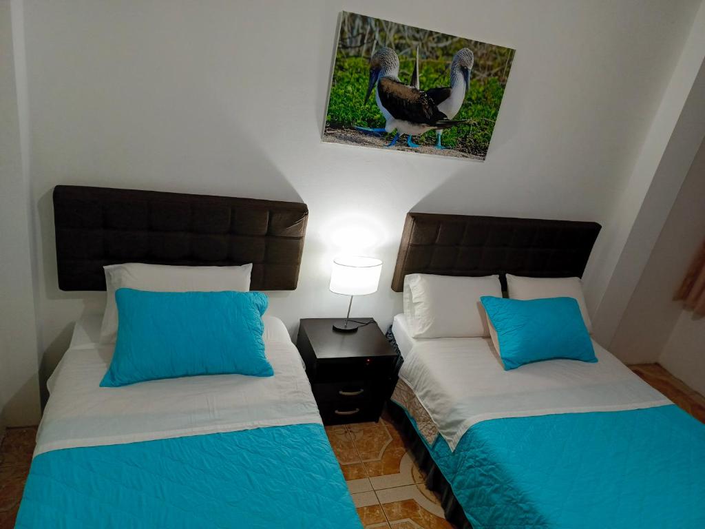 een slaapkamer met twee bedden en een kalkoen aan de muur bij Tesita's House habitación doble in Puerto Baquerizo Moreno