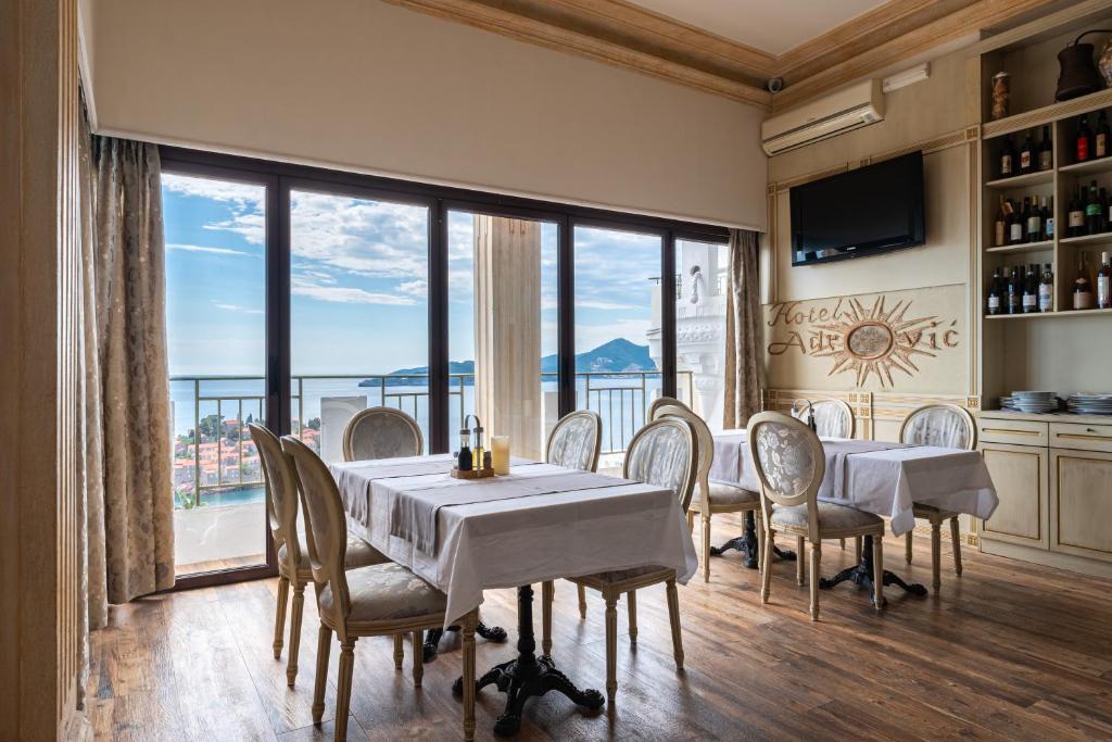 a dining room with tables and chairs and a large window at Hotel Adrović in Sveti Stefan