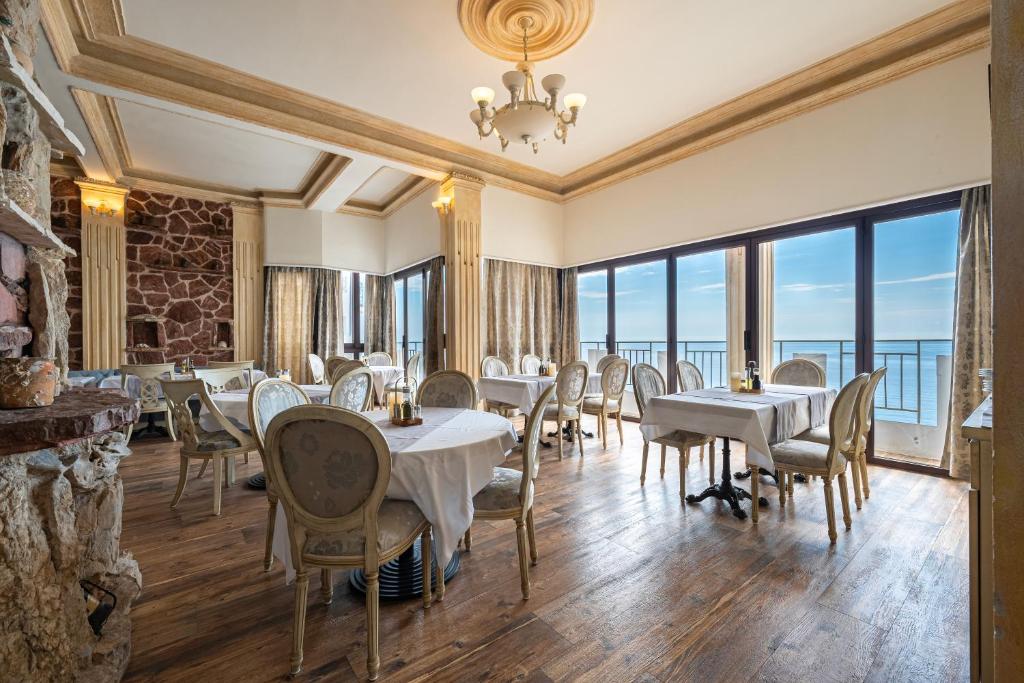 a restaurant with tables and chairs and large windows at Hotel Adrović in Sveti Stefan