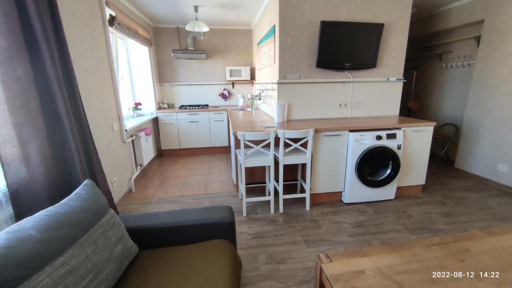 een kleine keuken met wasmachine en een woonkamer bij Butas prie vaikų parko in Ventspils