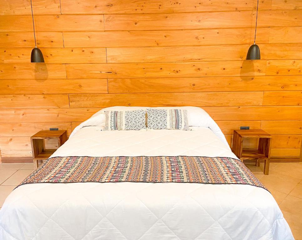 a bedroom with a white bed with wooden walls at Rayo de Luna in Monteverde Costa Rica