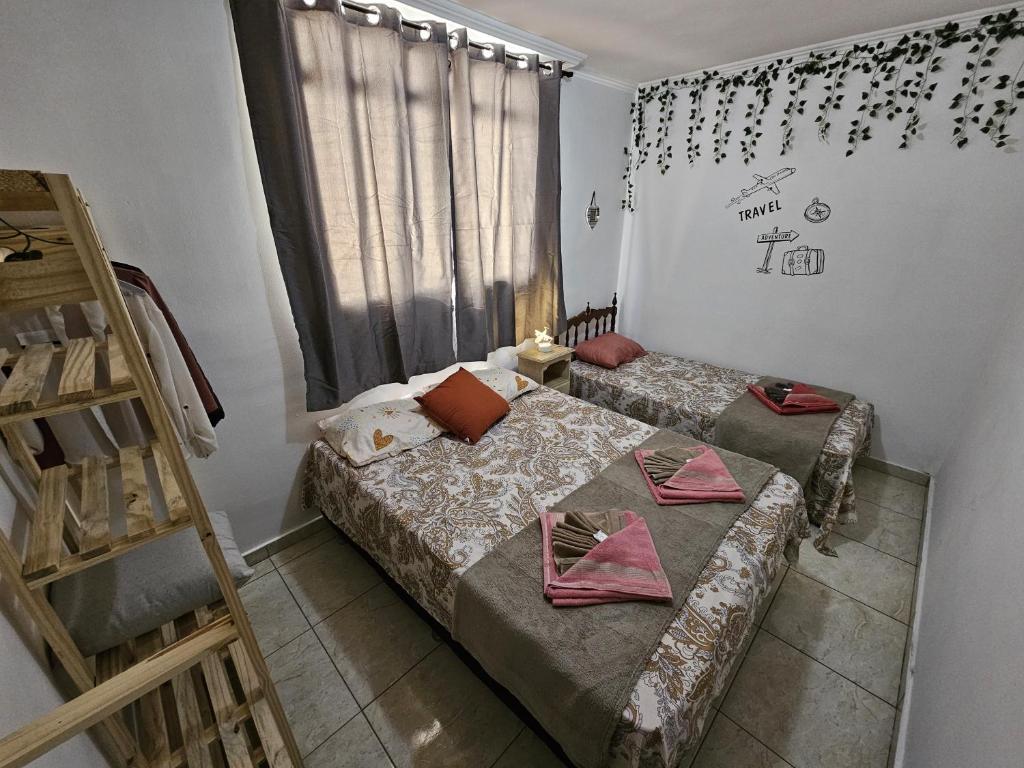 two beds in a small room with a window at AP 3 quartos -2min da ARENA MRV e Expominas- BH in Belo Horizonte