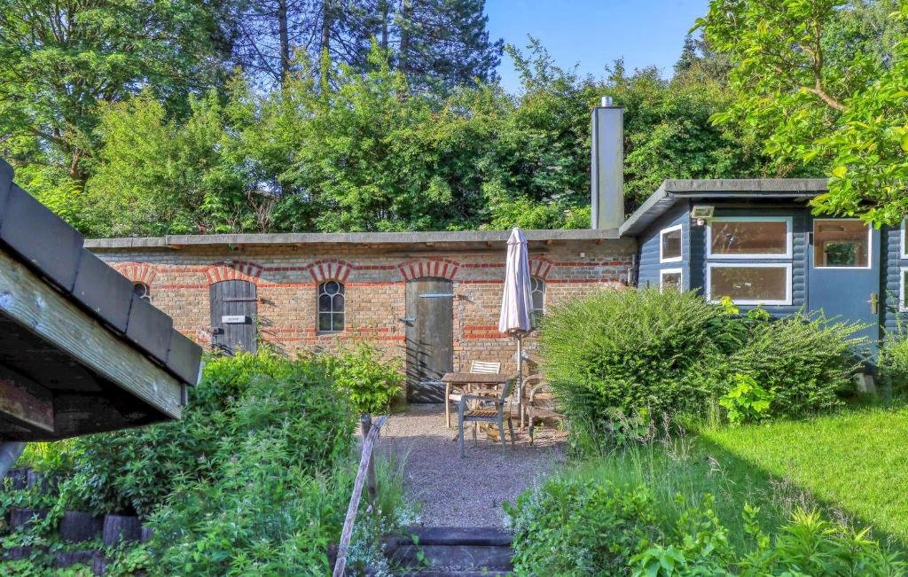 a garden with a brick building and a table with an umbrella at Waldblick in Glücksburg