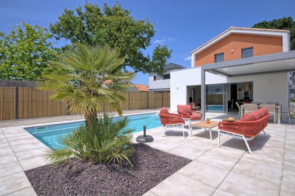 une cour avec une piscine, des chaises et un palmier dans l'établissement Family house with private pool, à La Baule
