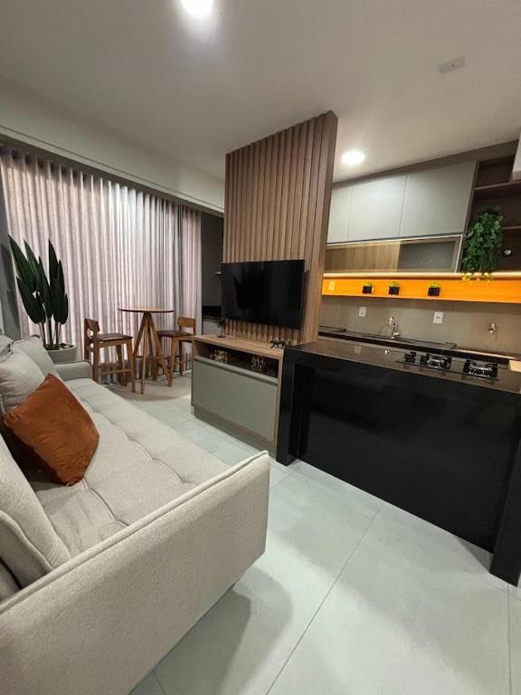 a living room with a white couch and a kitchen at Studio Live 1 Moderno e Aconchegante in Uberlândia