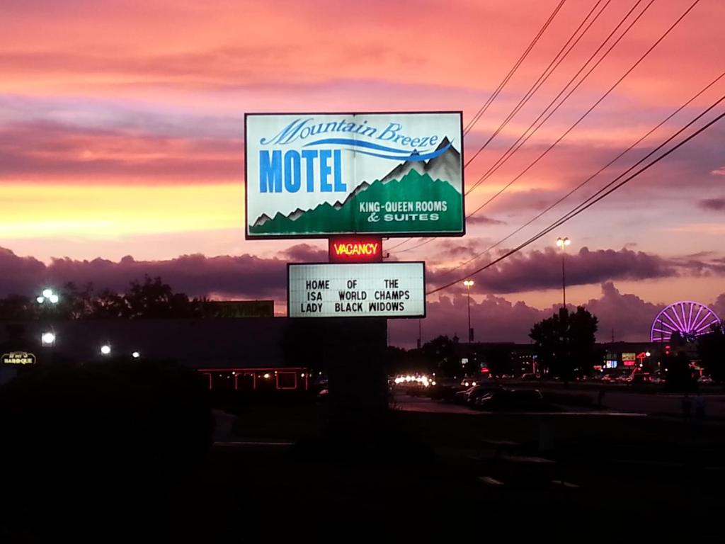 a motel sign on the side of a road with a sunset at Mountain Breeze Motel in Pigeon Forge