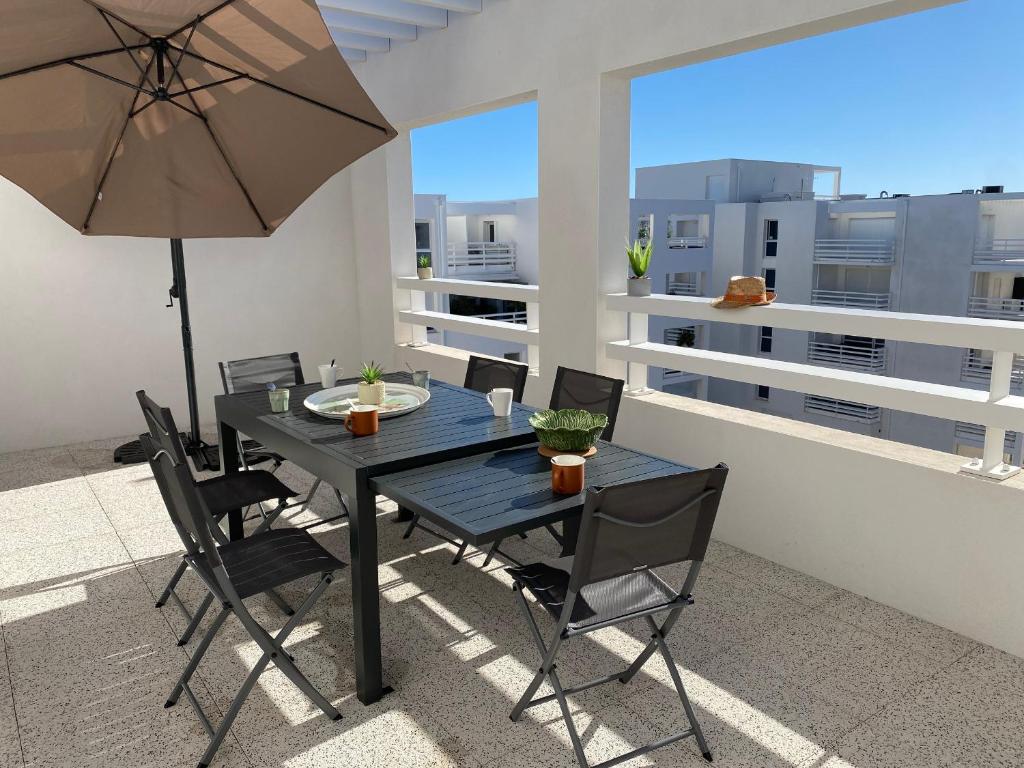 une table et des chaises avec un parasol sur un balcon dans l'établissement Duplex T4 Climatisé avec Terrasse, Parking et Plage à Proximité - Port Leucate, 8 Pers. - FR-1-798-1, à Leucate