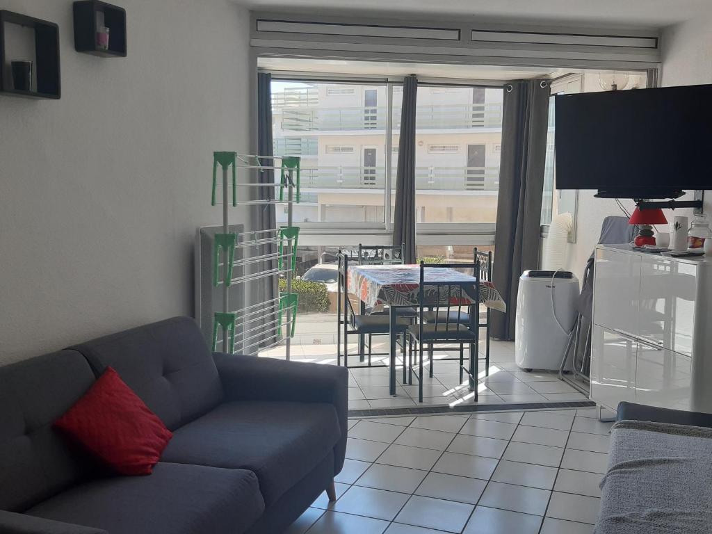 un salon avec un canapé et une table avec des chaises dans l'établissement Charmant T2 à Port Leucate - Proche Mer, Animaux Acceptés, Climatisation - FR-1-798-12, à Leucate