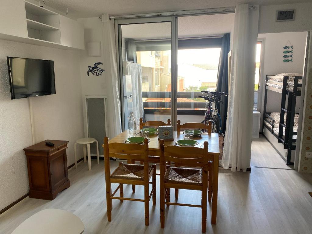 une salle à manger avec une table et des chaises et une fenêtre dans l'établissement Studio Cabine avec Loggia, Parking, Proche mer, TV, Lave-Linge, 2 Vélos, Port Leucate, 4 Pers. - FR-1-798-4, à Leucate
