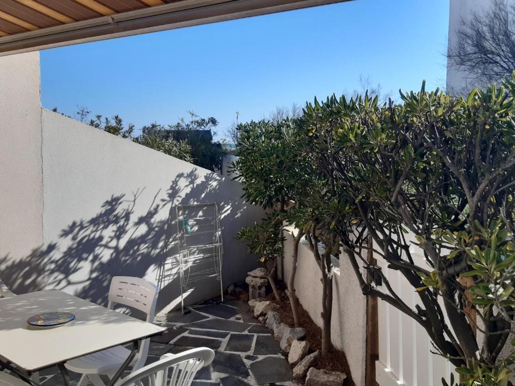 d'une terrasse avec une table et des chaises à côté d'un mur. dans l'établissement T2 Front de Mer, Rez-de-Chaussée, Port Leucate, Parking, 5 Personnes - FR-1-798-6, à Leucate