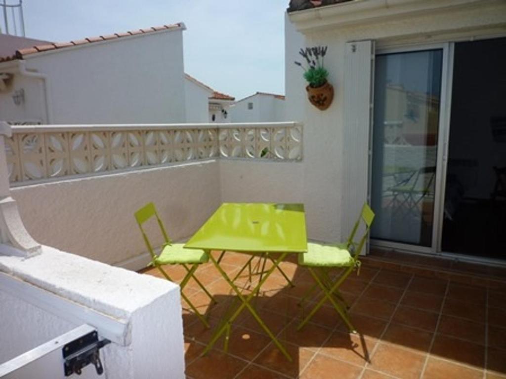 d'une table et de chaises vertes sur un balcon dans l'établissement Charmant T2 climatisé à Port Leucate - Terrasse, Parking, Proche Mer, Animaux Bienvenus - FR-1-798-24, à Leucate