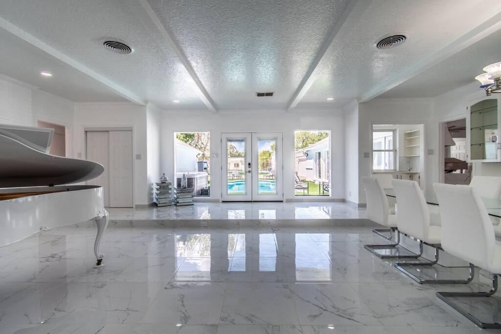 a white living room with a piano and chairs at Poolside Opulence Tennis and HotTub in Corpus Christi