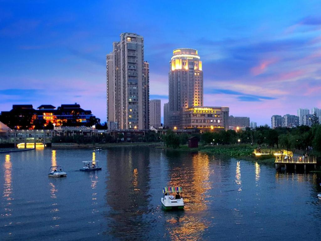 a city skyline with boats in the water at night at Kinho Narada Hotel in Xianliangzhongchang
