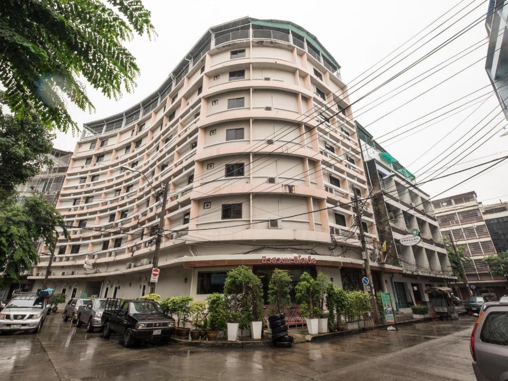 a tall building with cars parked in front of it at New Suanmali Hotel in Bangkok
