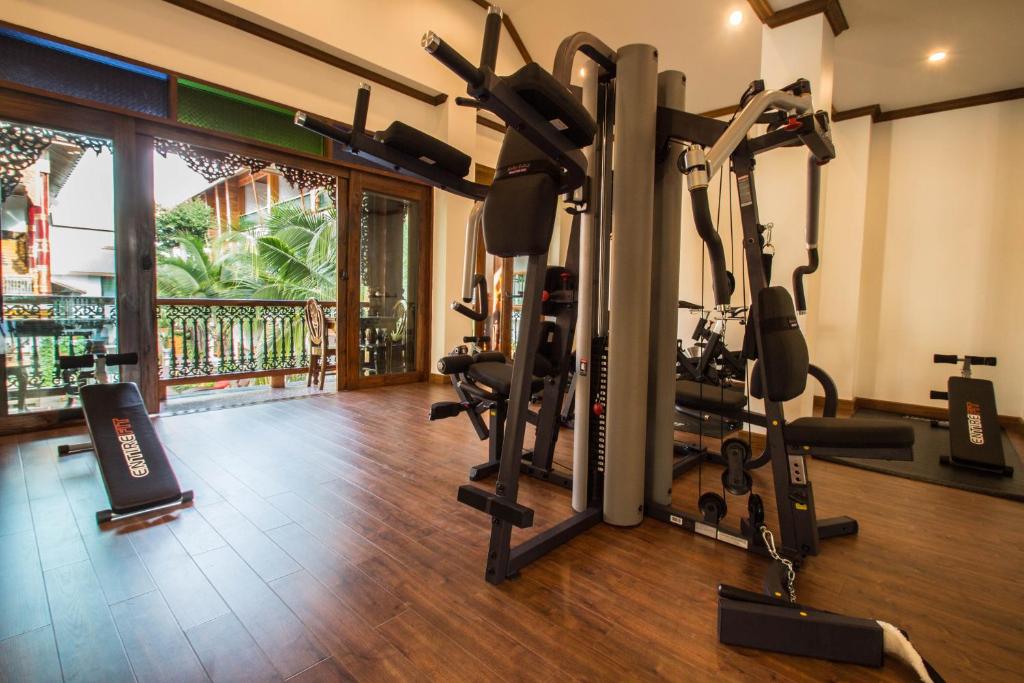 A wood-floored fitness room with a large cable machine beside open balcony doors.