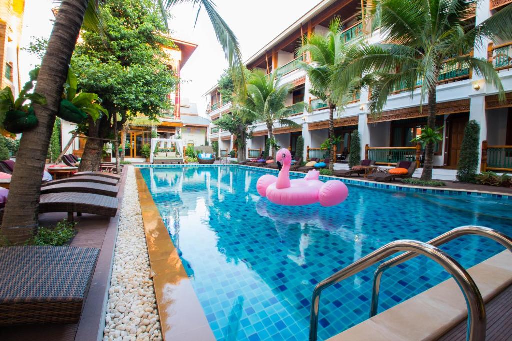 A long blue-tiled courtyard pool surrounded by palms, loungers and hotel balconies.