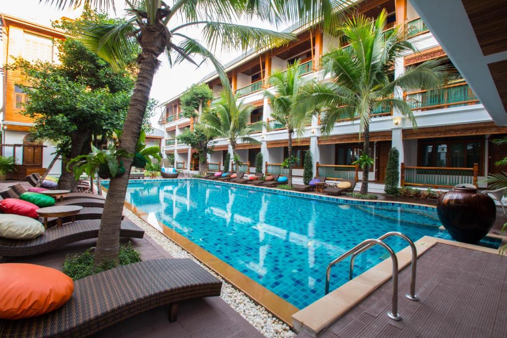A palm-lined courtyard pool with woven loungers, colourful cushions and surrounding balconies.