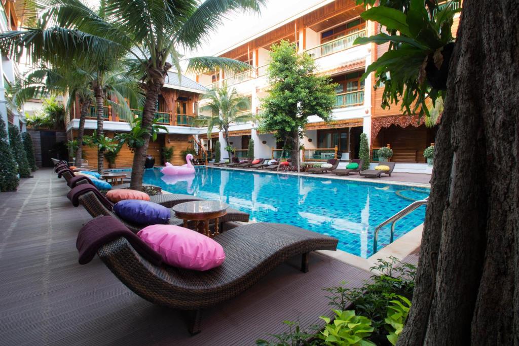 A courtyard pool lined with cushioned chaise lounges and tropical planting.