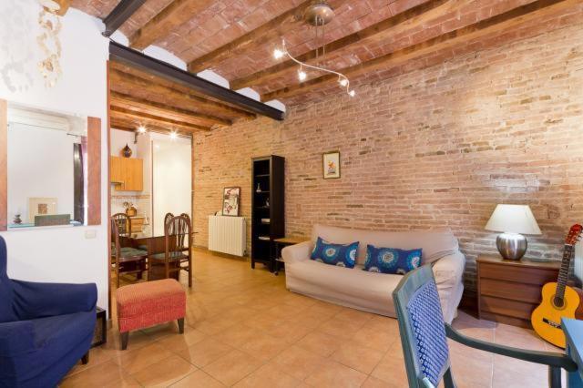 a living room with a couch and a brick wall at Flat Plaza de España BCN in Barcelona