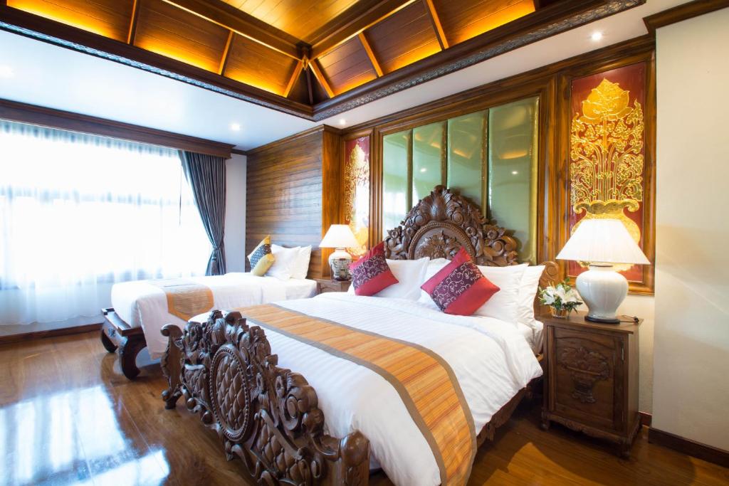 A spacious-looking bedroom with twin beds, a carved wooden footboard and a bright curtained window.