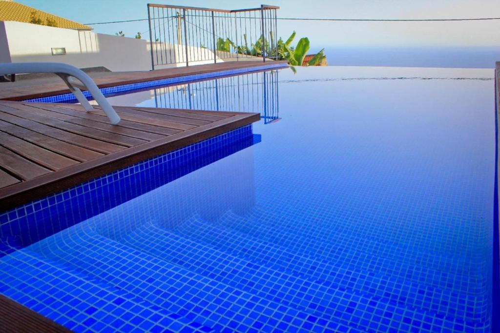 a swimming pool with a deck and blue water at Ferienhaus in Estreito Da Calheta mit Privatem Pool und Meerblick in Jardim do Mar