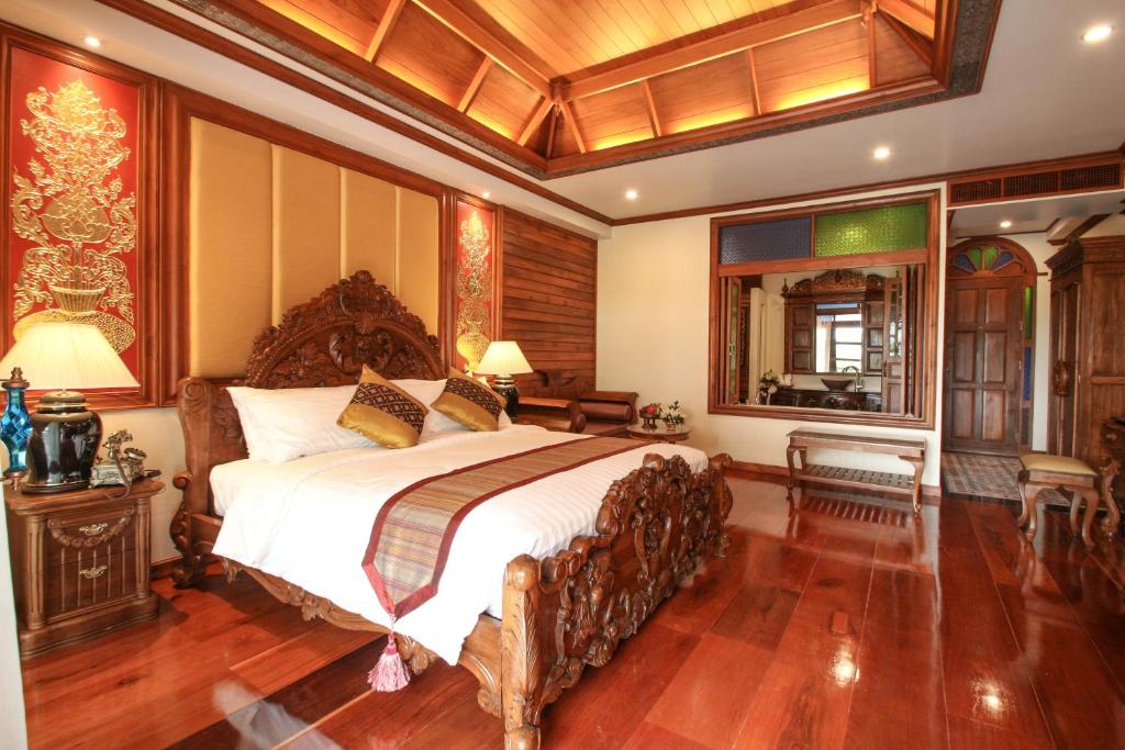 A richly carved bedroom with a four-poster-style bed and traditional Thai-inspired interiors.