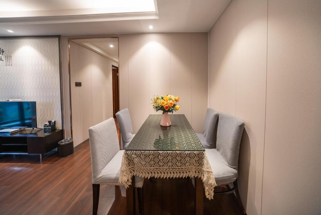 a dining room table with chairs and a vase of flowers on it at Shenzhen Binhe Impression Hotel Apartments in Shenzhen
