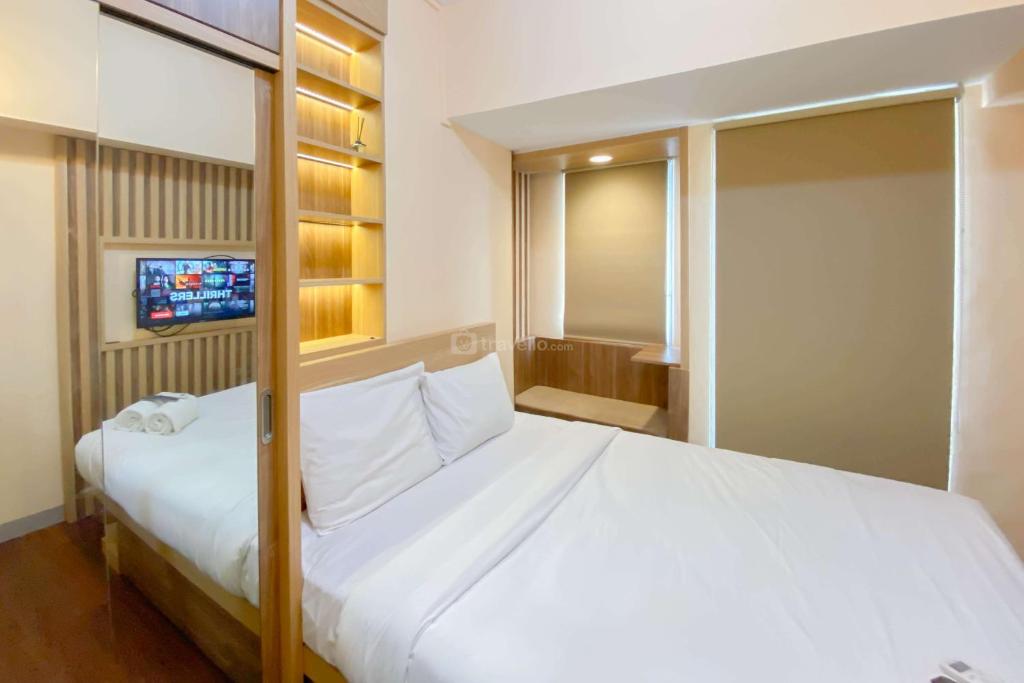 RawalembangにあるGood and Simply Studio Tokyo Riverside PIK 2 Apartment By Travelioの大きな白いベッドとテレビのある寝室