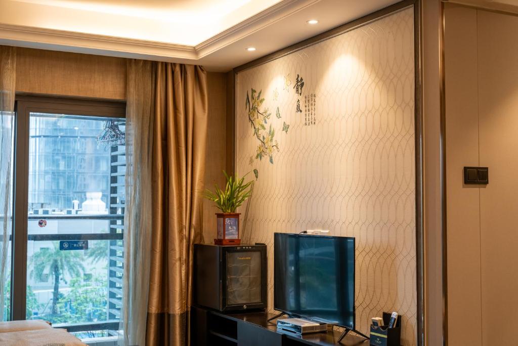 a hotel room with a tv and a window at Shenzhen Binhe Impression Hotel Apartments in Shenzhen