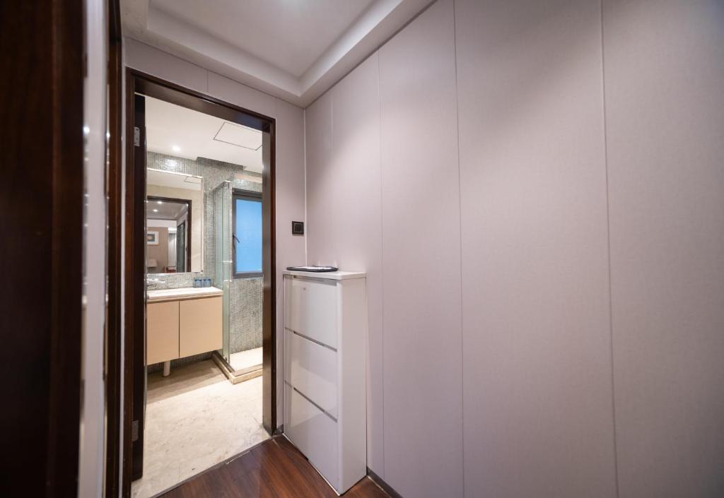 a bathroom with a mirror and a white wall at Shenzhen Binhe Impression Hotel Apartments in Shenzhen