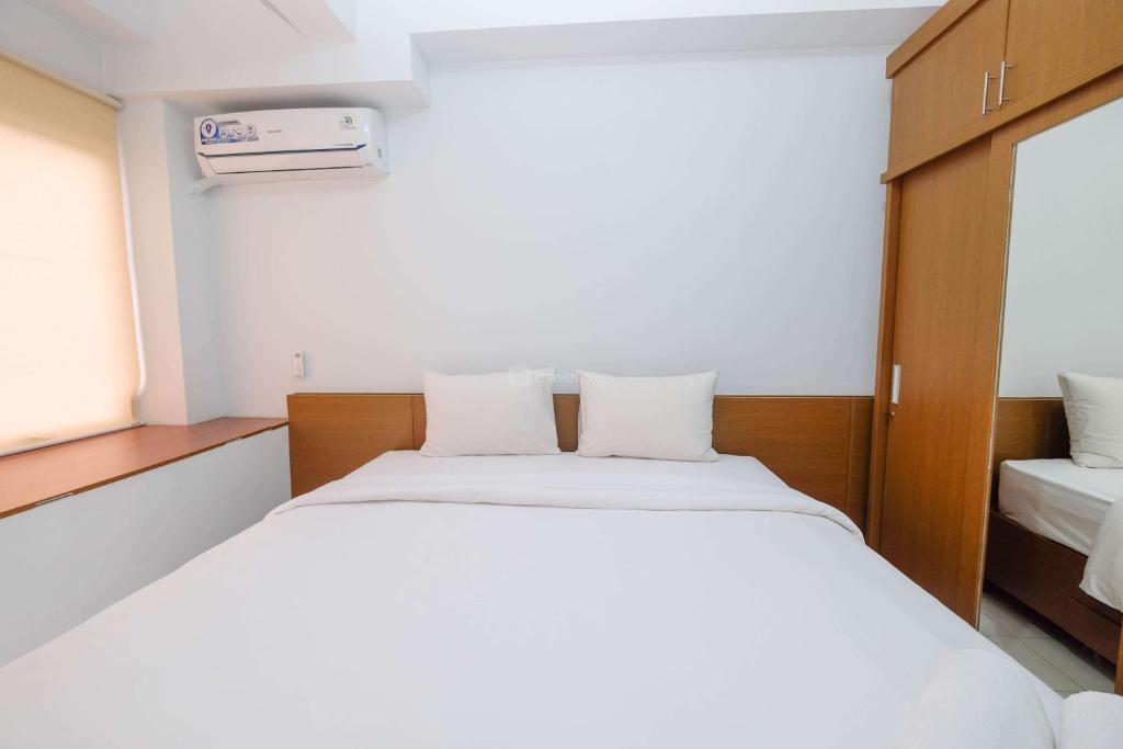 a bedroom with a large white bed and a window at Luxurious Studio at Patraland Urbano Apartment By Travelio in Bekasi