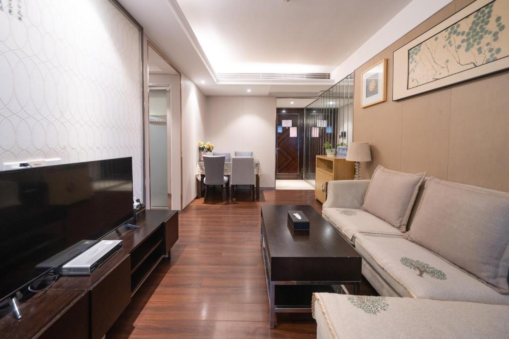 a living room with a couch and a flat screen tv at Shenzhen Binhe Impression Hotel Apartments in Shenzhen