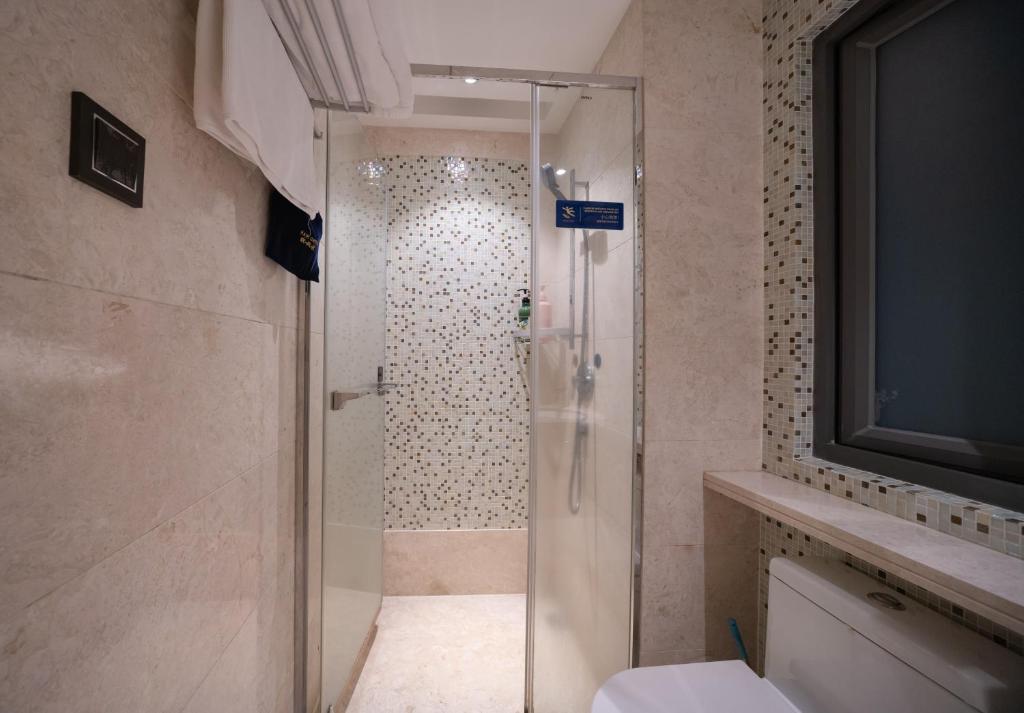a shower with a glass door in a bathroom at Shenzhen Binhe Impression Hotel Apartments in Shenzhen