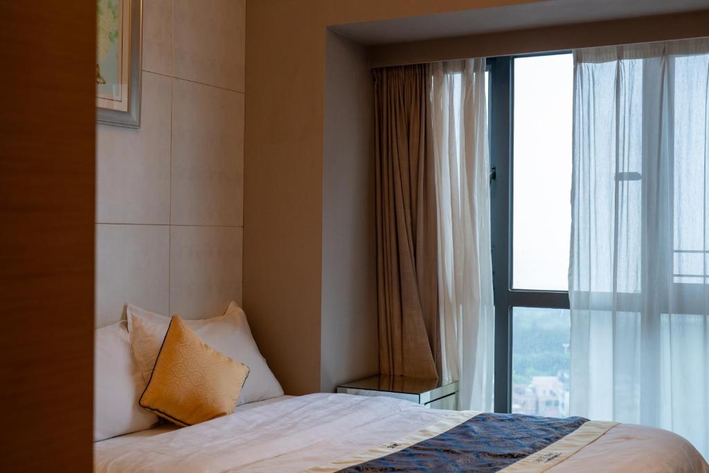 a bedroom with a bed and a large window at Shenzhen Binhe Impression Hotel Apartments in Shenzhen