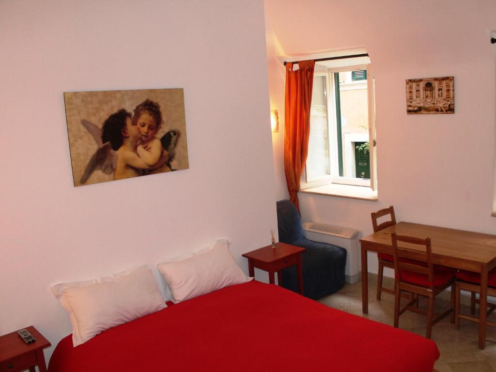 ローマにあるRoman Forum Holiday Foriのベッドルーム1室(赤いベッド1台、ダイニングルームテーブル付)