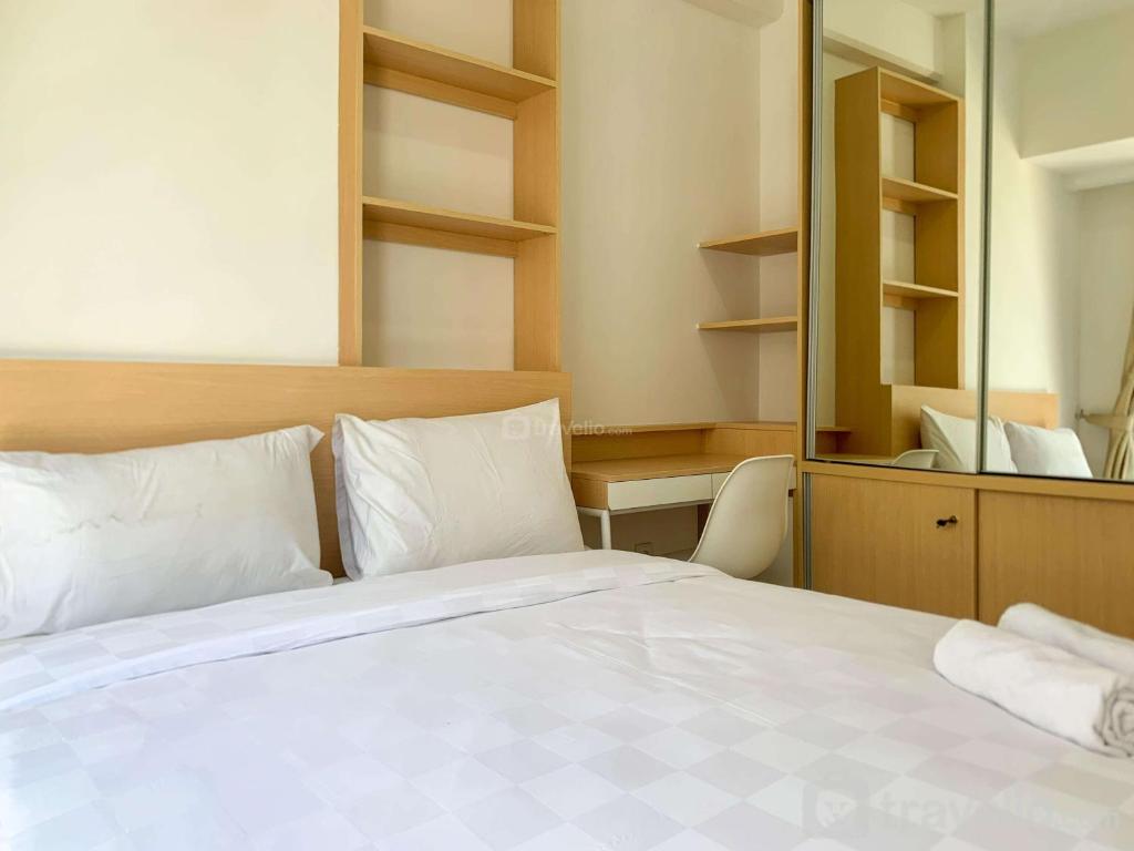 een slaapkamer met een wit bed en een spiegel bij Relaxing 2BR at 35th Floor Tokyo Riverside PIK 2 Apartment By Travelio in Rawalembang