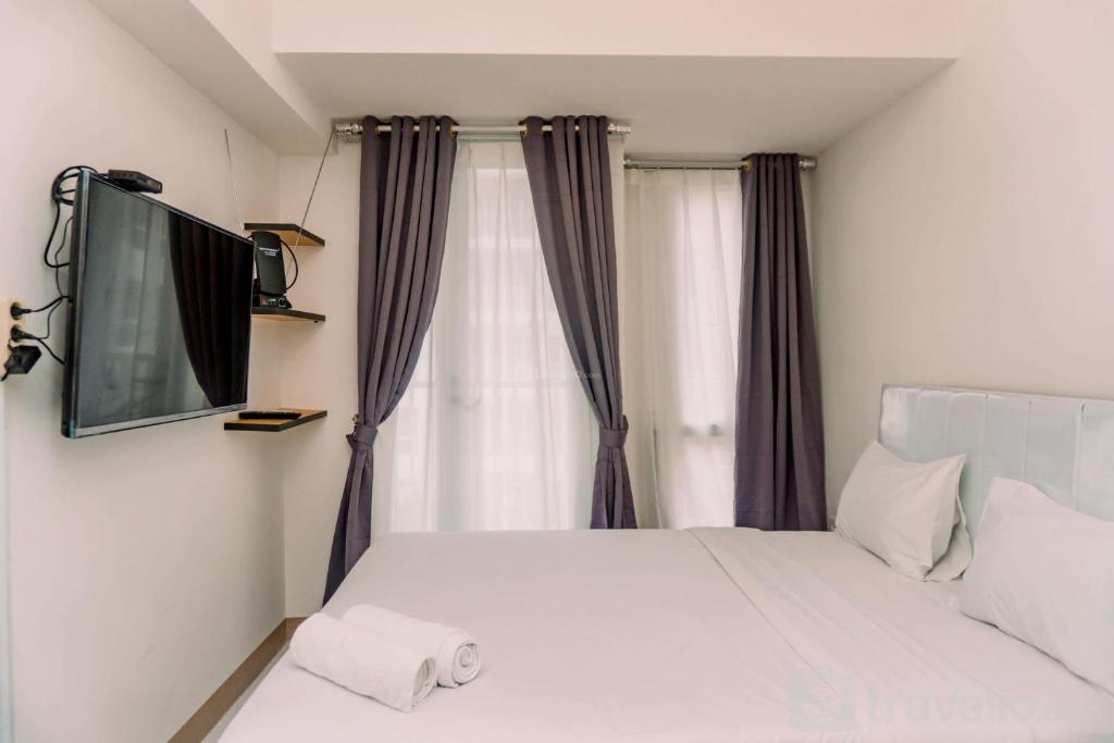 a bedroom with a bed with a tv on the wall at Nice and Comfort Studio Apartment at Tokyo Riverside PIK 2 By Travelio in Rawalembang