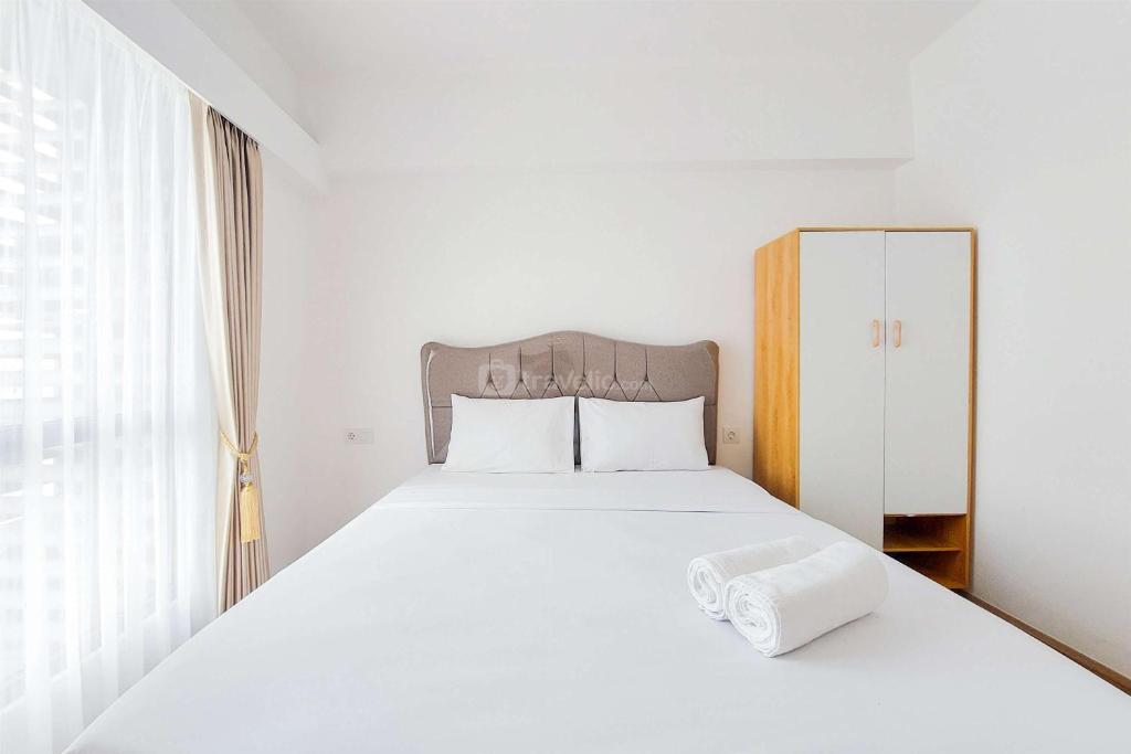 a bedroom with a white bed and a window at Strategic and Simple 3BR Sky House BSD Apartment By Travelio in Tangerang