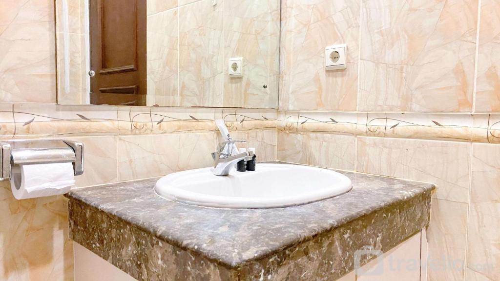 a bathroom with a white sink and a mirror at Homey and Comfort Stay 2BR Bellezza Apartment By Travelio in Jakarta