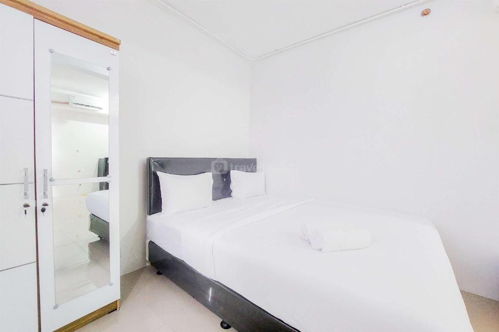 タンゲランにあるWell Furnished with Cozy Designed Studio Urbantown Serpong Apartment By Travelioのベッドと鏡のある白い寝室